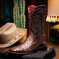 Man seated wearing brown Alabama ostrich skin cowboy boots paired with blue jeans