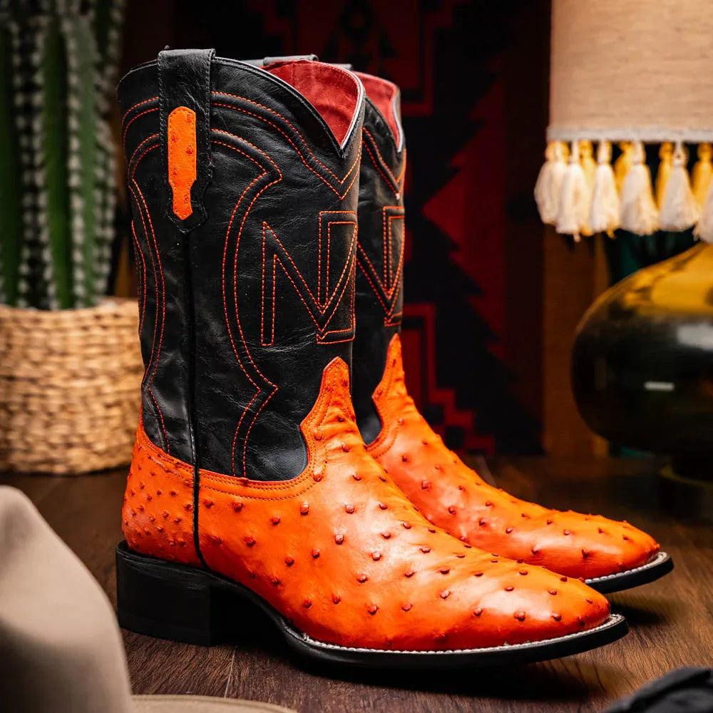 Man wearing Alabama orange ostrich cowboy boots outdoors, showing square toe and leather.