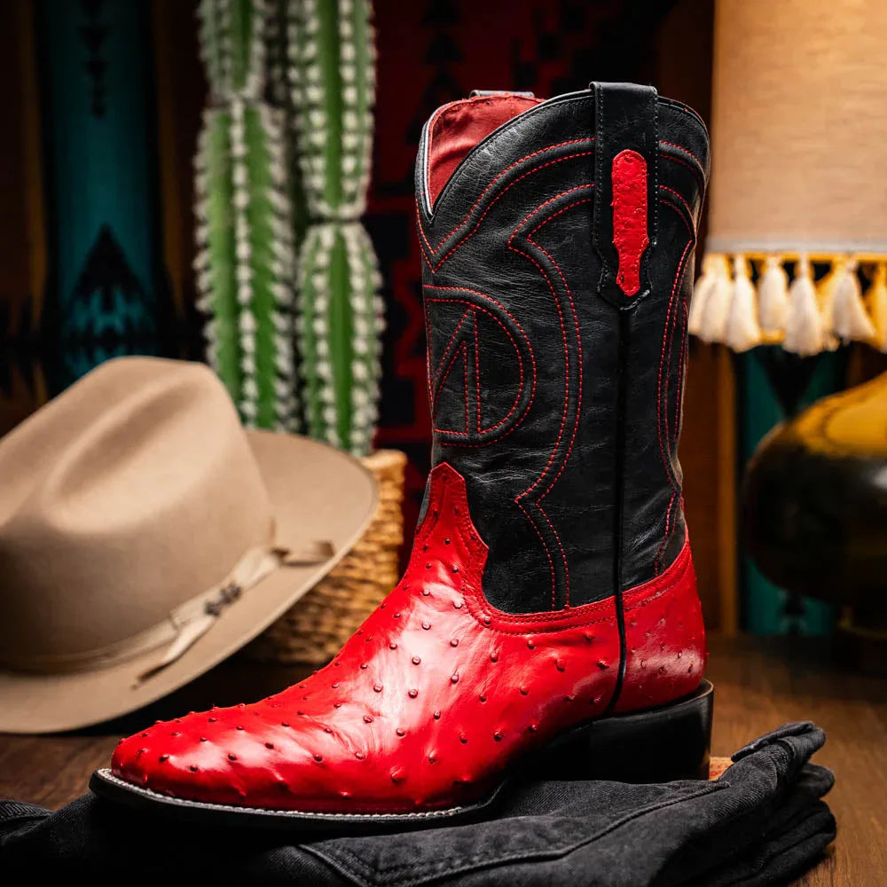 Man walking outdoors wearing Alabama Red ostrich cowboy boots with casual dark pants.