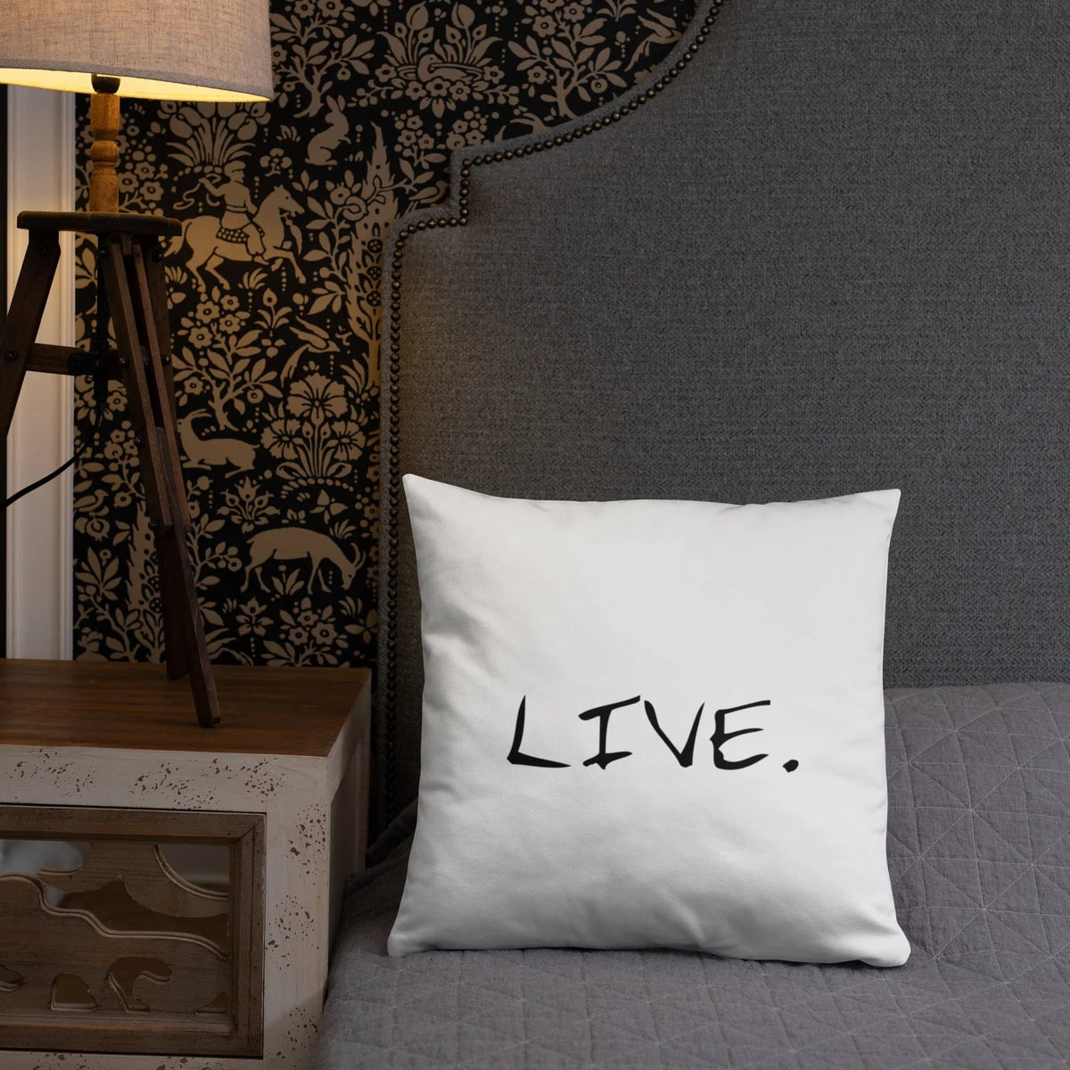 White pillow on a beige armchair next to a small wooden table with books