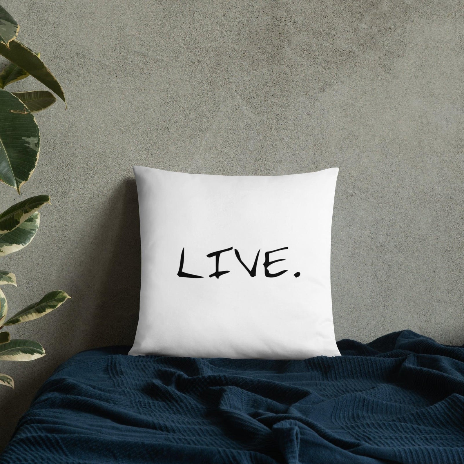 White square pillow on a beige chair near a wooden table with a laptop and cup