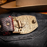 Man showing Arkansas Belt's antique brass buckle detail while dressed in cowboy outfit.