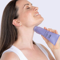 Close-up of a woman applying serum to her neck with rollerball applicator, highlighting smooth skin.