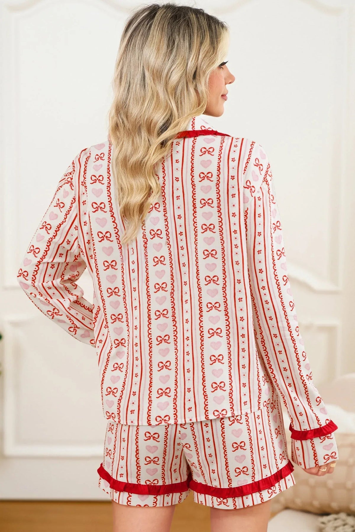 Front view of long-sleeve pink heart bow pajama shirt paired with matching shorts on hanger.