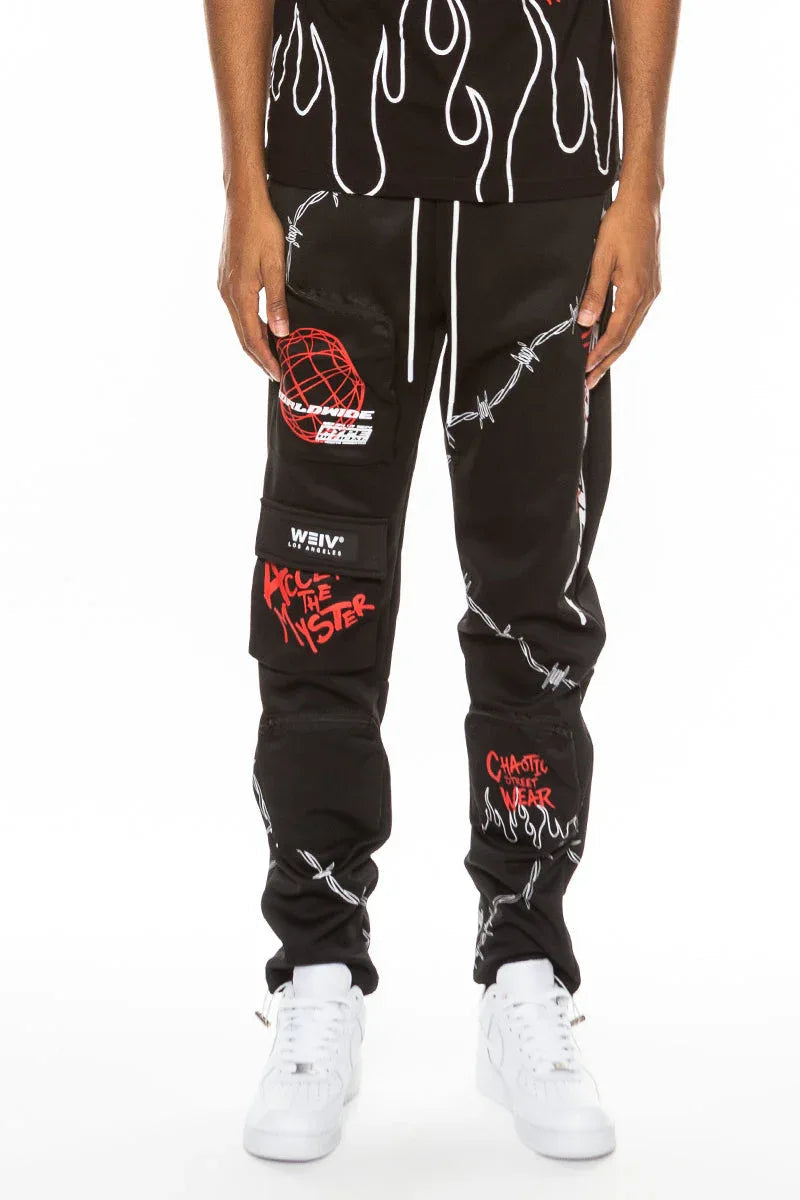 Black men's track pants laid flat showing standard zipper pockets and printed design detail