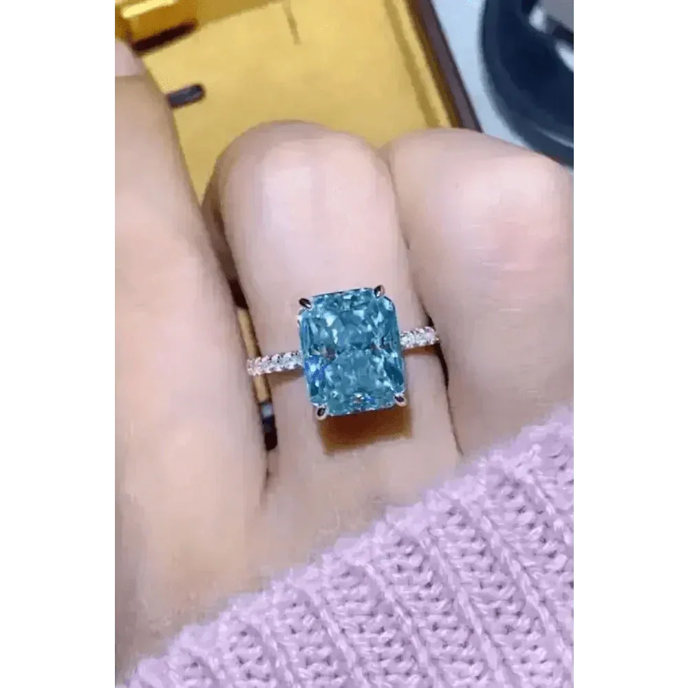 Side angle showing sparkling blue gemstone and silver band of the ring