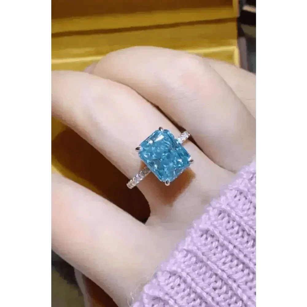 Top view of blue moissanite gemstone ring on black fabric background