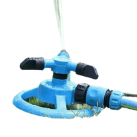 Blue automatic sprinkler evenly watering vibrant green grass in backyard.