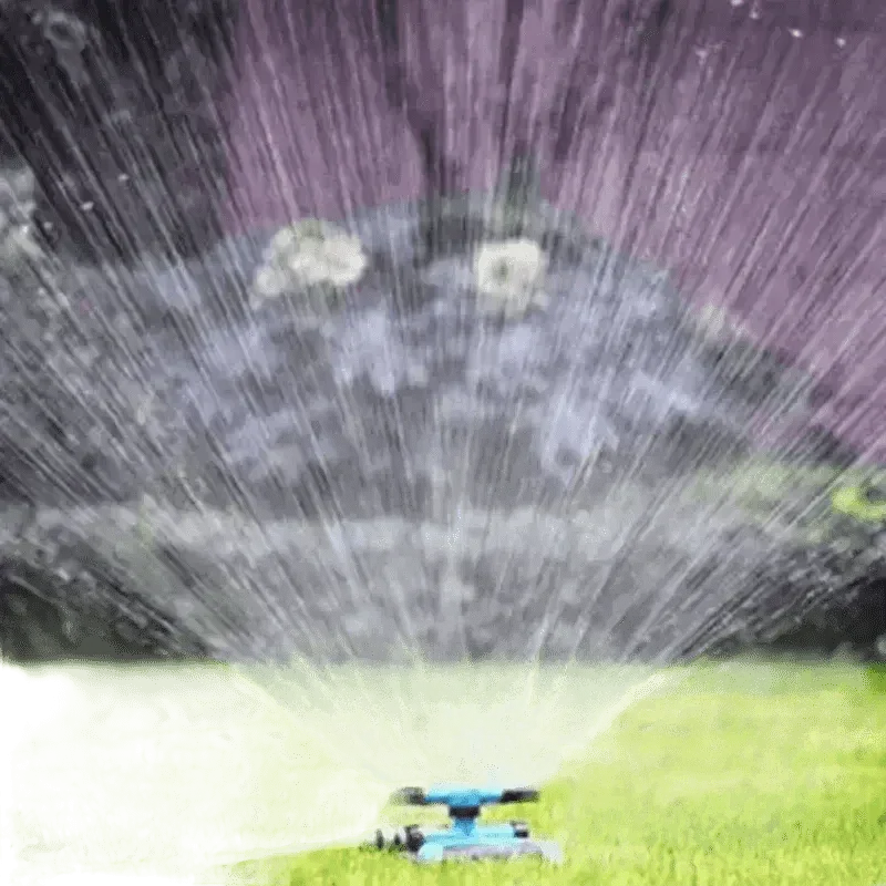 Blue garden sprinkler rotating and watering lush green grass outdoors.
