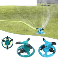 Close-up of blue rotating sprinkler head distributing water droplets over lawn.