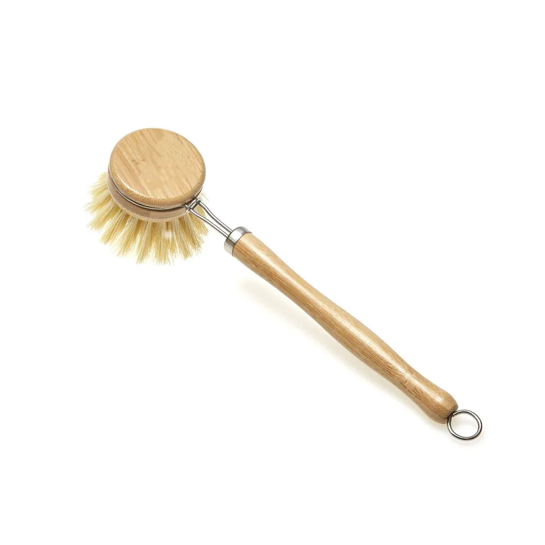 Close-up of bamboo handle dish brush with natural sisal bristles angled on a white surface.