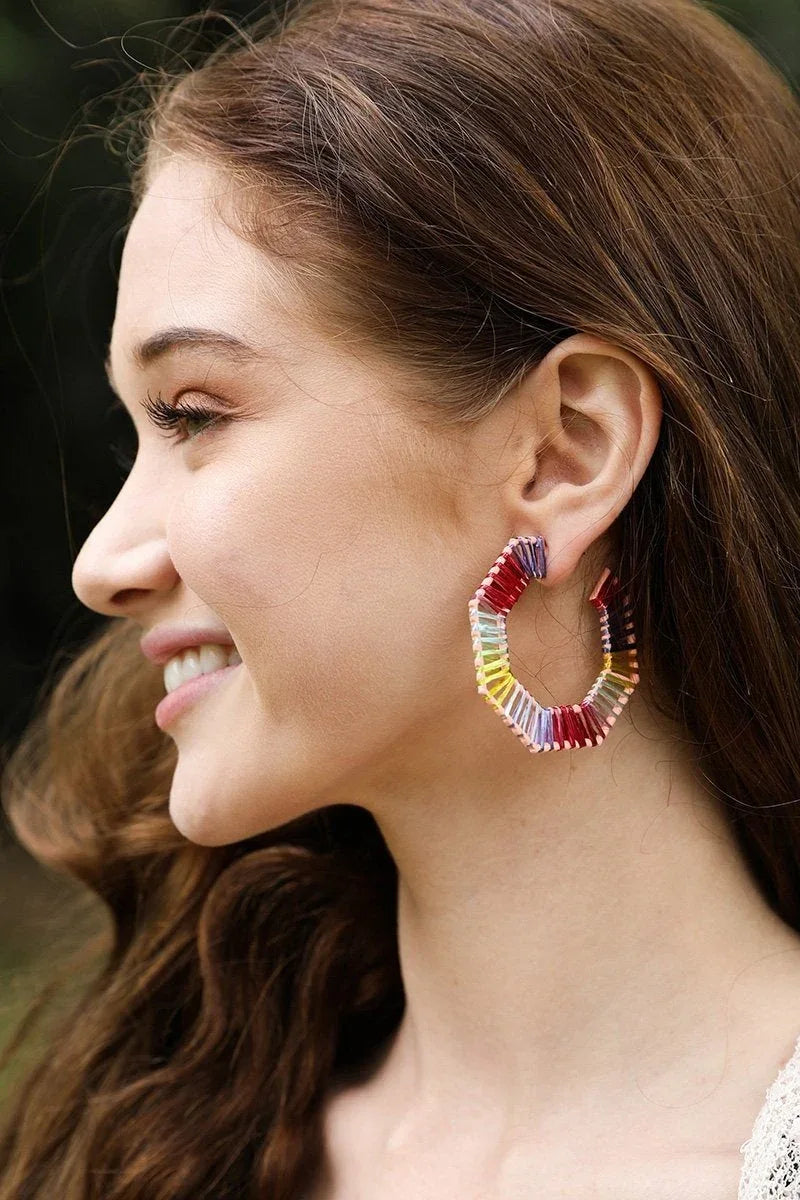 Close-up of colorful raffia hoop earrings with vibrant, woven texture and clip closure on a white background.