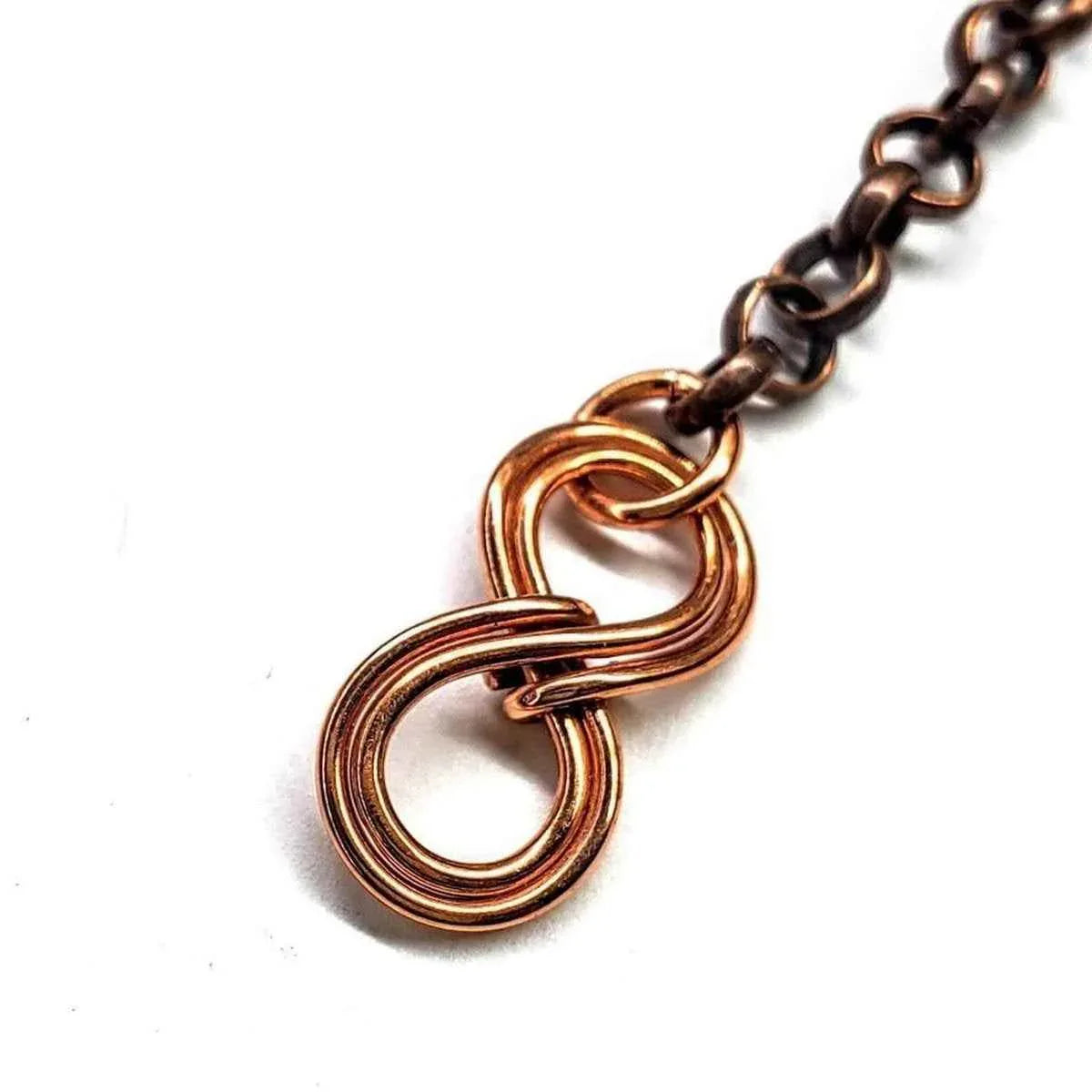 Hand-hammered copper wire heart pendant with turquoise and silver beads paired with infinity symbol.