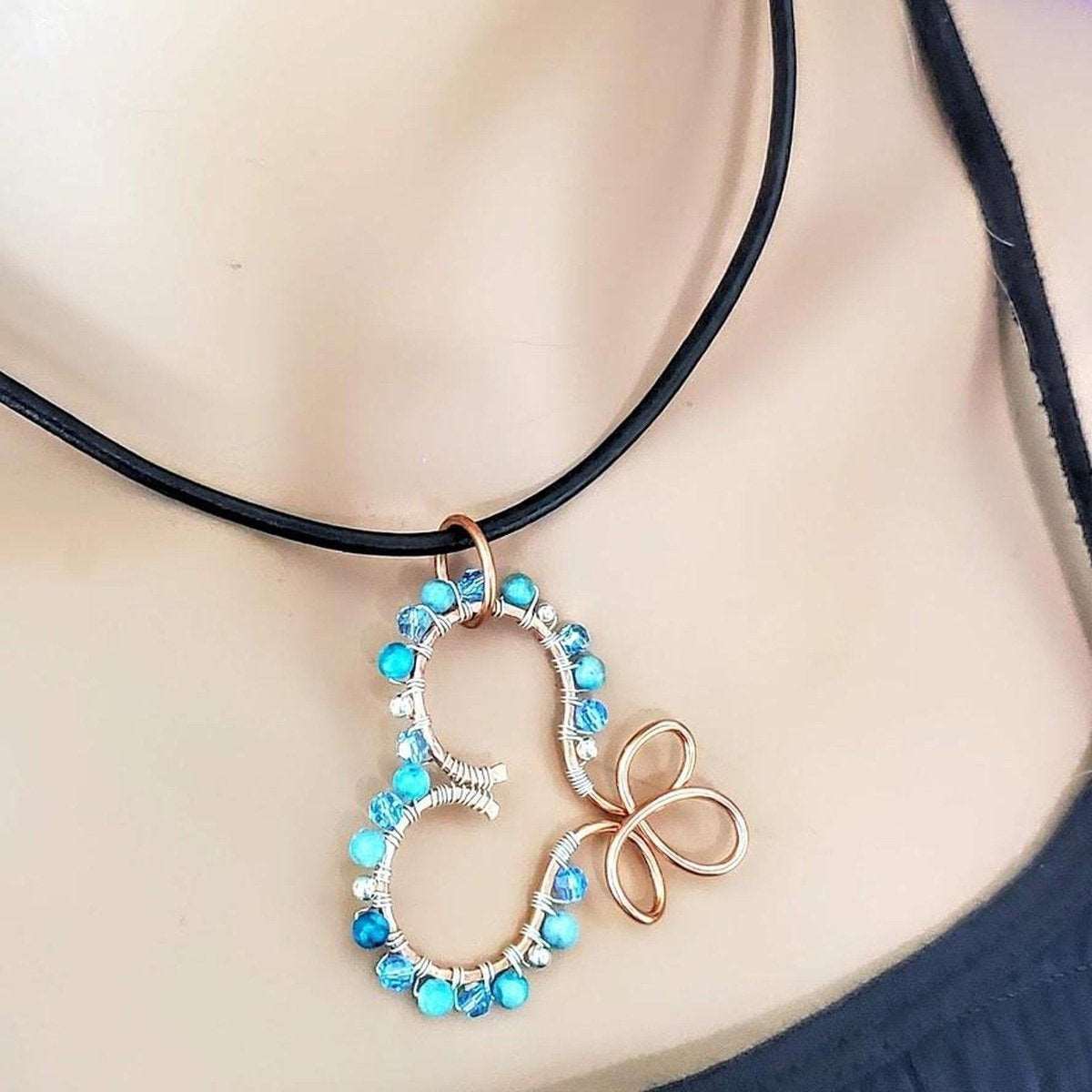 Top angle of copper wire heart pendant wrapped with turquoise jasper and silver beads on leather strap.