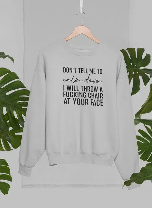 Grey sweatshirt on hanger in front of palm trees, showing side angle