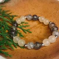 Close-up of natural gray and white agate gemstone beads with silver spacers on elastic bracelet.