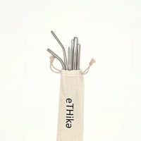 Set of eleven stainless steel straws of various sizes arranged neatly with a mini cotton carrying pouch.