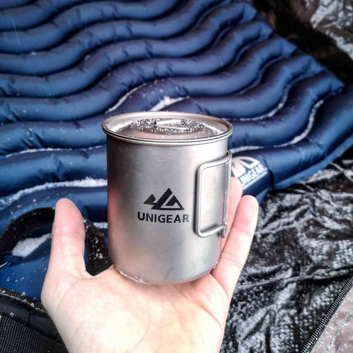 A lightweight, 450ml titanium camping cup with folding handles, shown on a wooden surface.