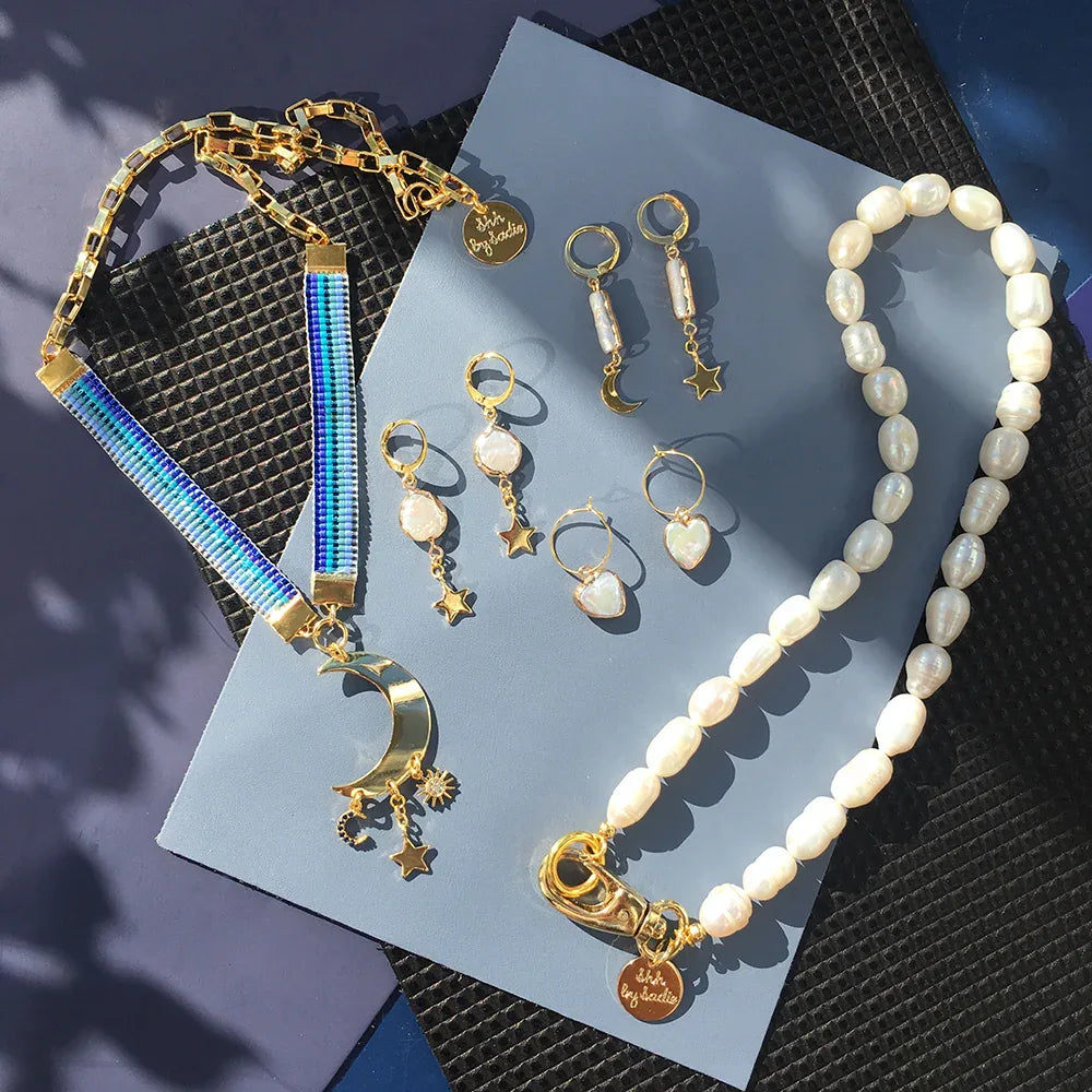 Pair of gold plated mini hoop earrings featuring a turquoise crystal moon and chunky heart charm.