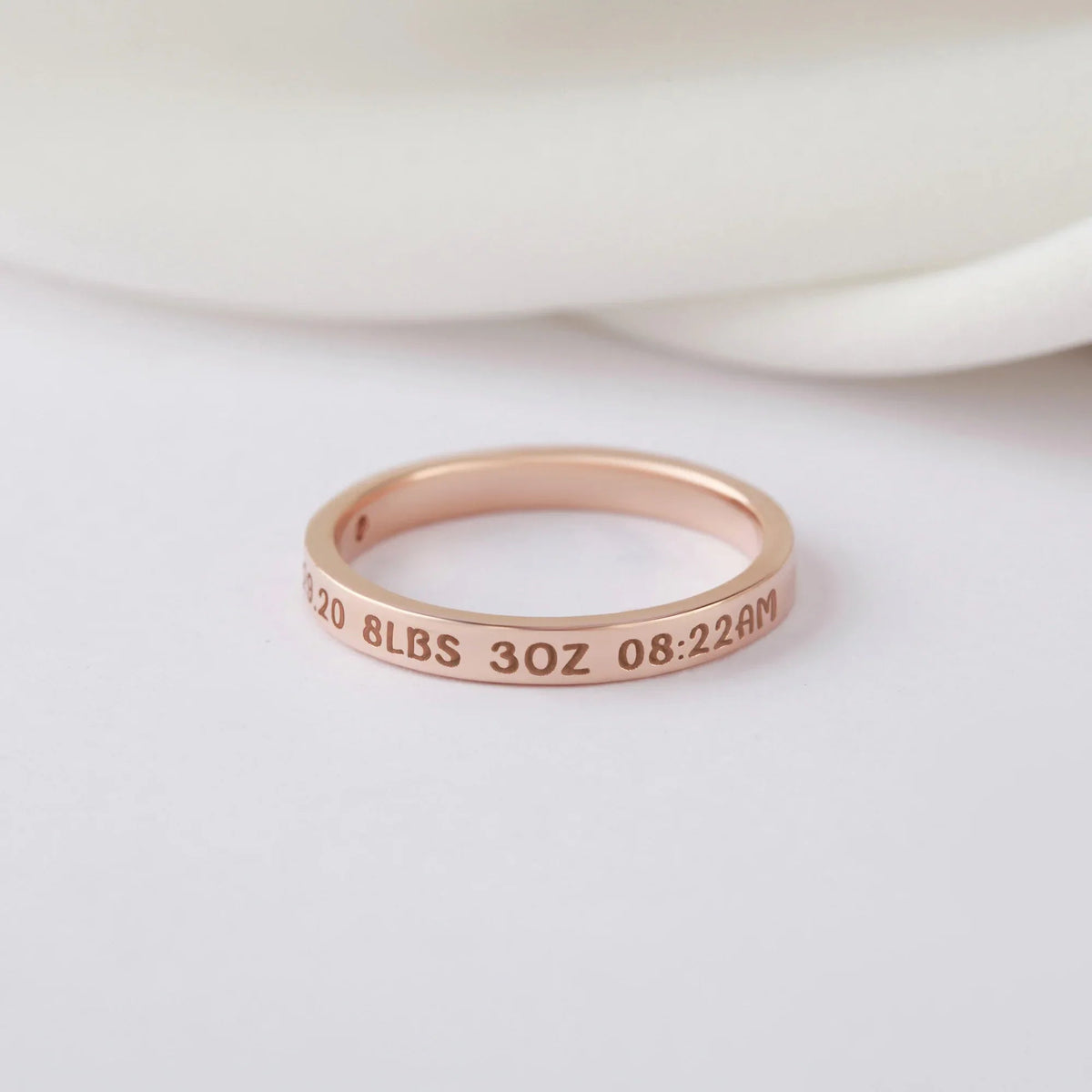 Personalized silver ring resting on textured fabric, highlighting fine engraving for new moms.