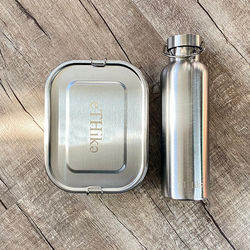 Open stainless steel lunchbox showing flexible divider separating different food types.