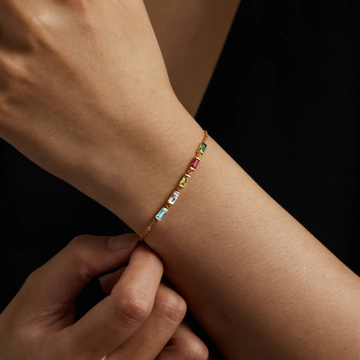 Flat lay of mom bracelet alongside birthstone gemstones arranged on a soft fabric.