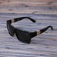 Black square-framed Jase New York Carter sunglasses angled to show temple arms and pyramid detail.
