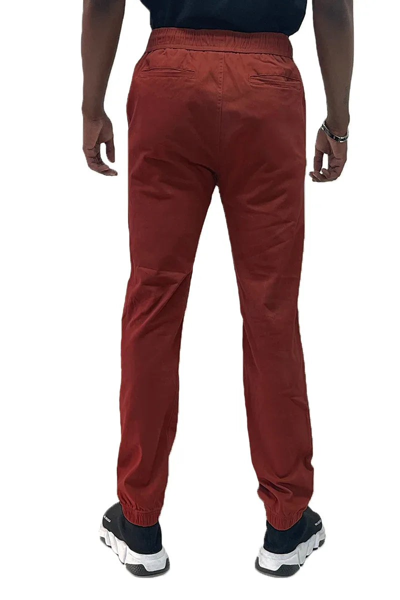 Back view of jogger pants highlighting two back pockets and elastic waist on a plain surface.