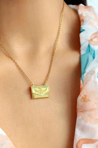 Gold envelope locket necklace with a delicate daisy engraving, displayed on a neutral background.