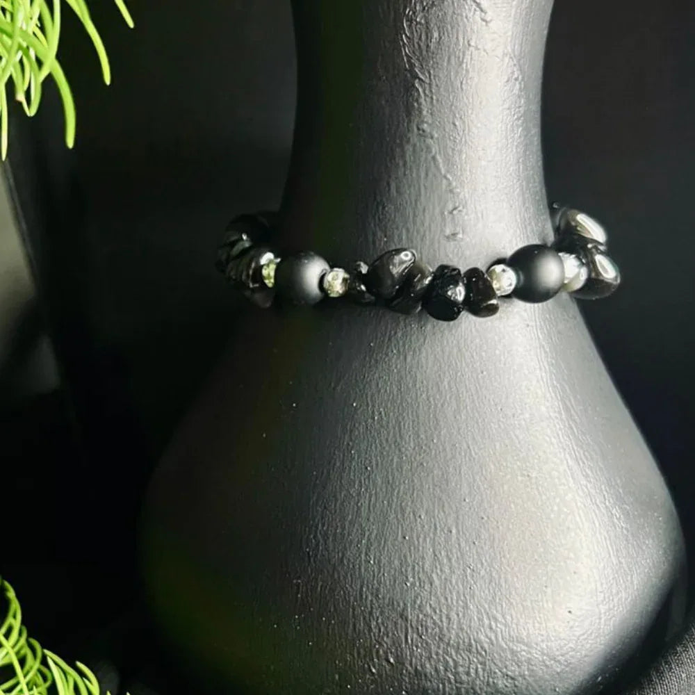 Detailed view of natural black stone chips forming a stretch cord bracelet.