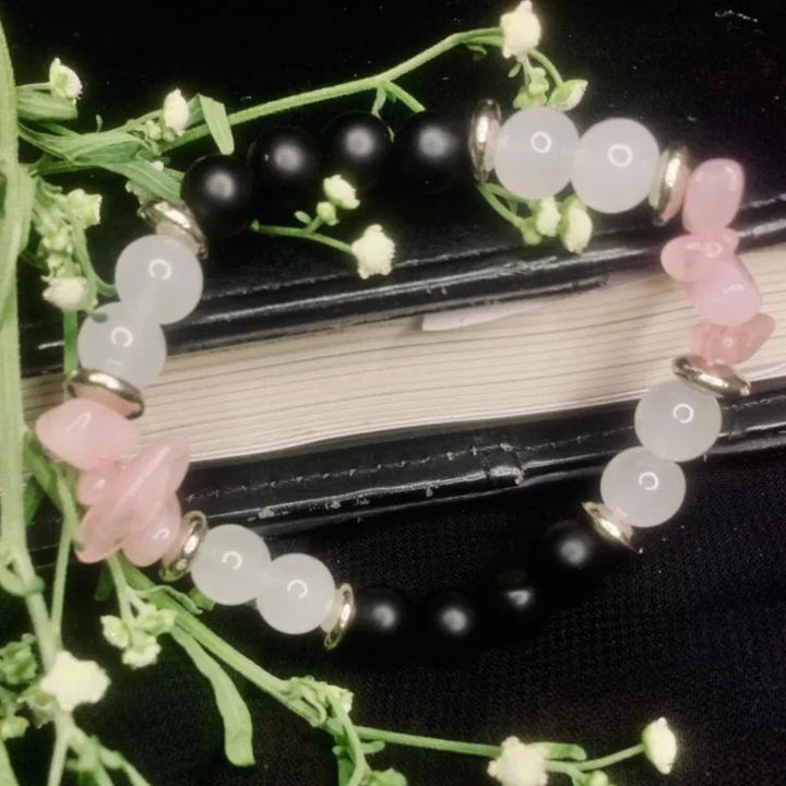 Close-up of handmade bracelet with black onyx, white jade, and rose quartz beads with silver spacers