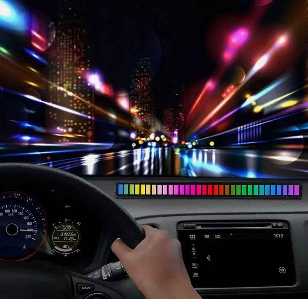 RGB light bar mounted on a car dashboard glowing in rainbow colors at night with city lights ahead