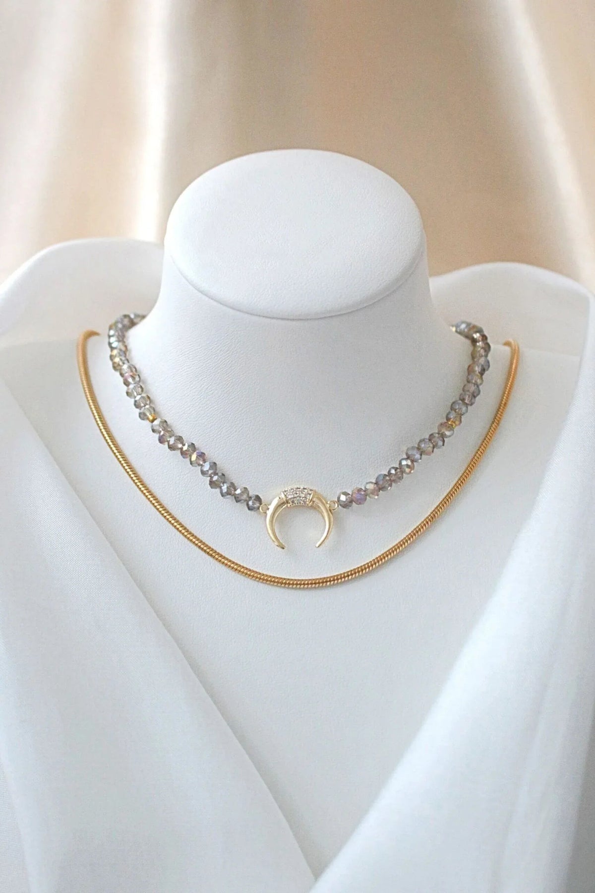 Hands holding the adjustable light blue chrome Austrian crystal choker with gold-plated charm.