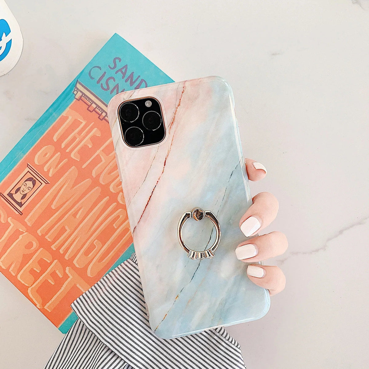 Marble iPhone case resting on a flat surface with natural light reflections.
