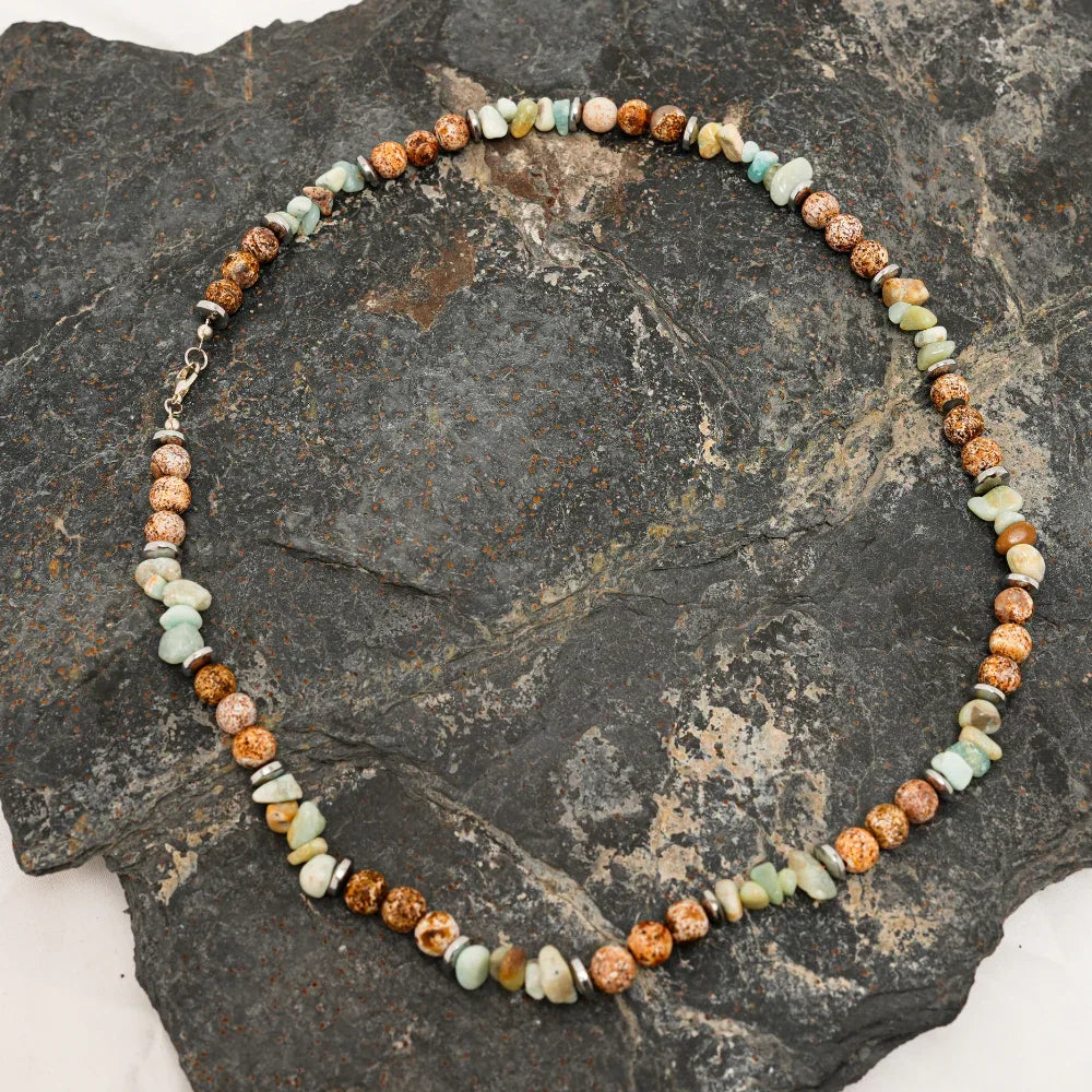 Artistic arrangement of natural agate stone necklace beads with earthy brown and green hues.