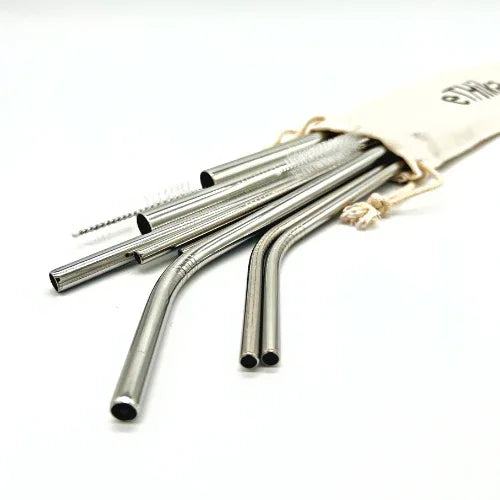 Close-up image showing seven stainless steel straws in a row with a cleaning brush beside them.