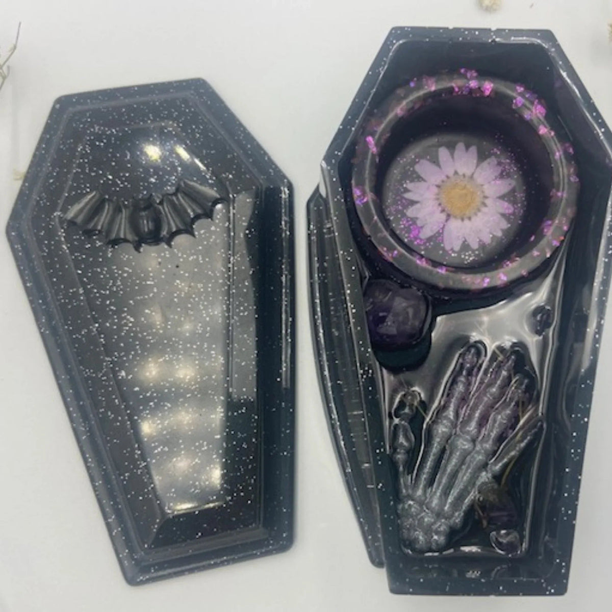 Handcrafted black resin coffin candle holder featuring amethyst stones, dried flowers, and central hole for incense.