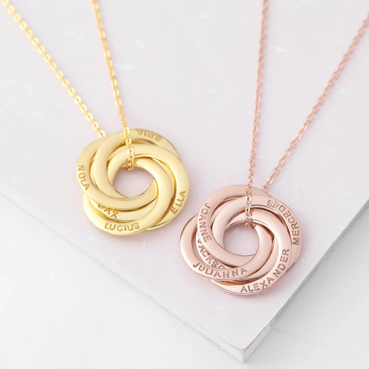 Hand holding silver personalized necklace with three interlocked rings symbolizing family bond.