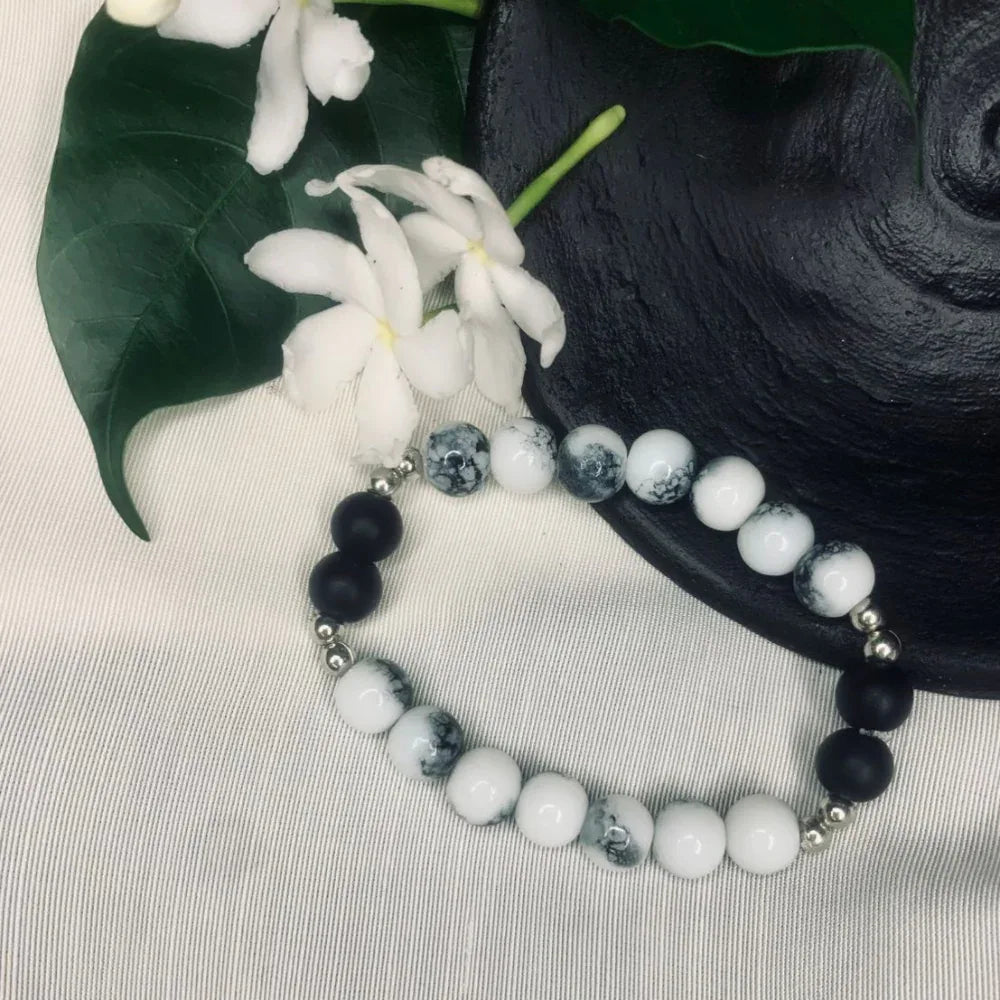 Side angle of stretch bracelet combining natural white howlite and smooth black onyx beads.