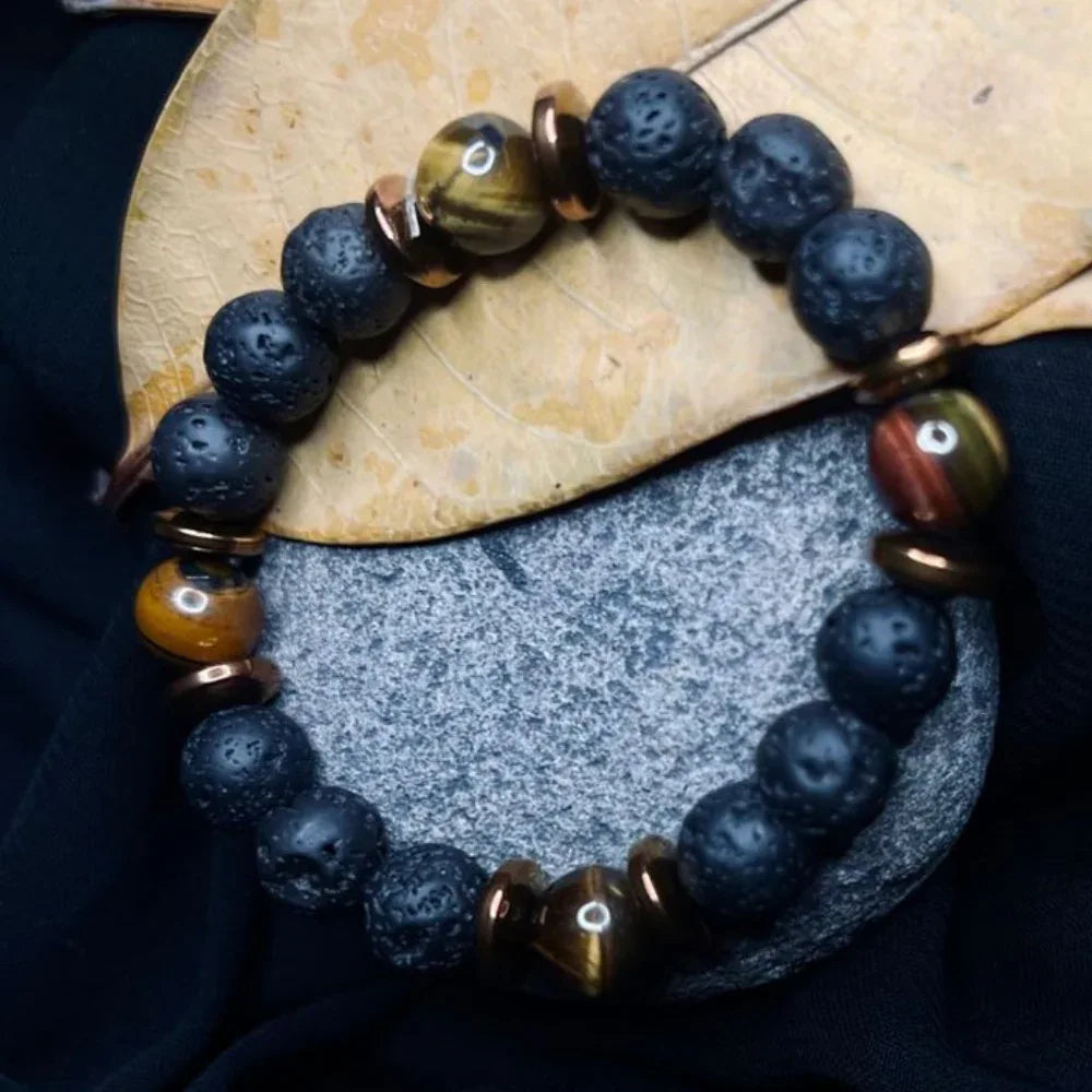 Close-up of Black Lava and Tiger Eye stone bracelet with copper spacers on white background.