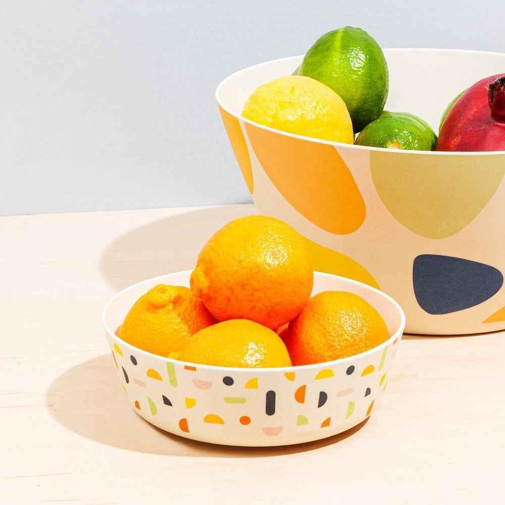 Four vibrant bamboo bowls featuring various eco-friendly designs, shown from top view.
