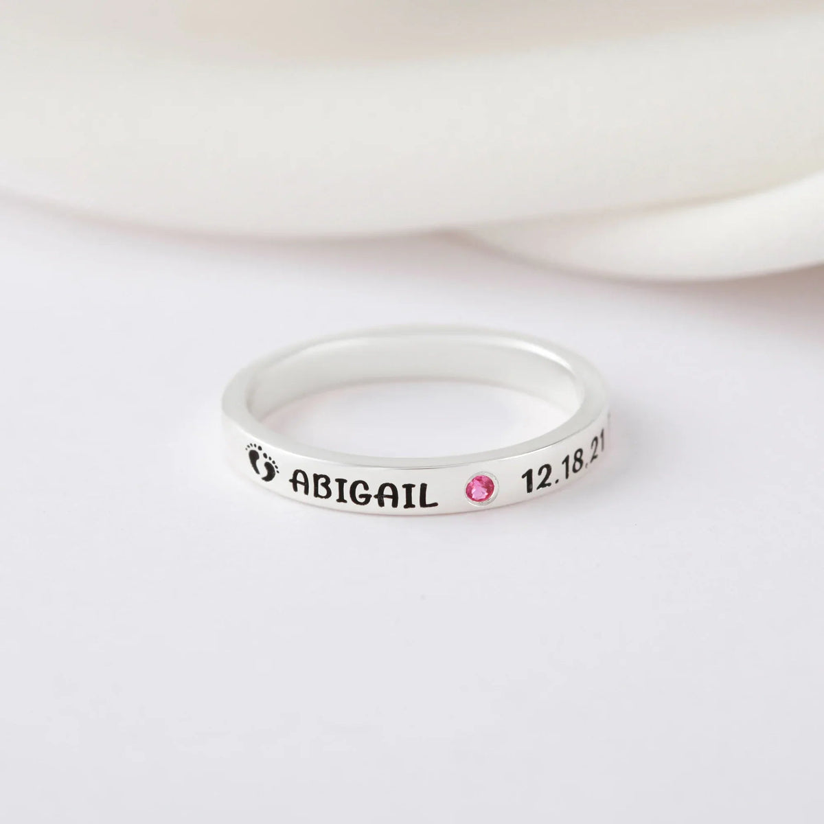 Silver name ring displayed on a white background showcasing delicate engraving details.