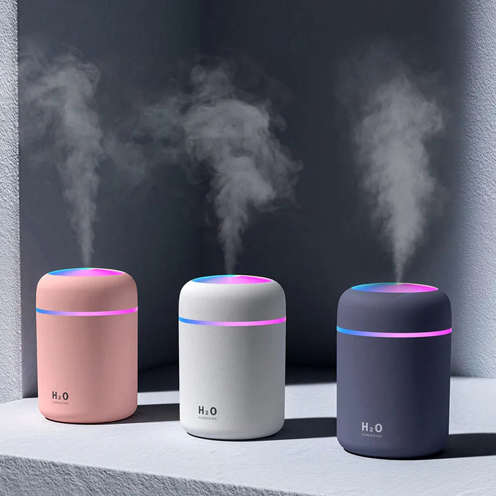 Compact white portable air humidifier with 300ml tank and colorful night light on wooden table.