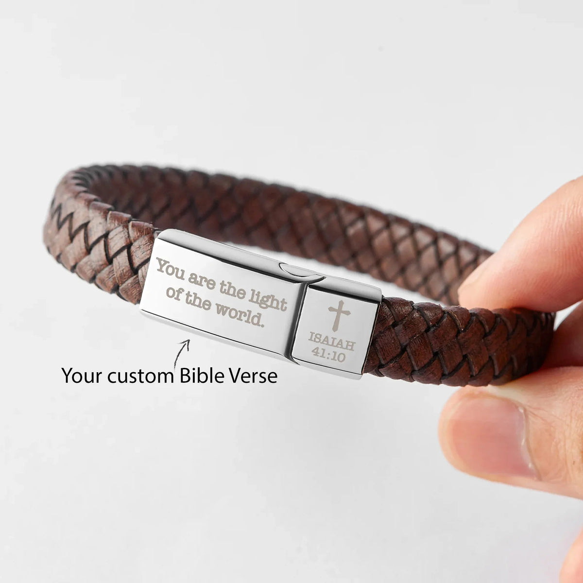 Brown leather Christian bracelet coiled showing clasp and detailed cross on stainless steel plate.