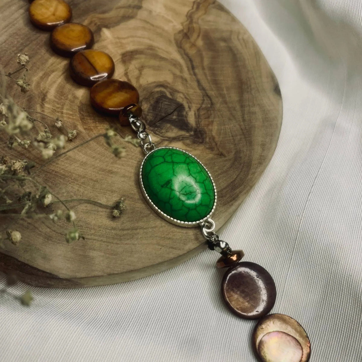 Detailed look at vibrant green turquoise centerpiece surrounded by smooth brown beads.