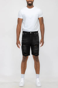 Close-up of the distressed fabric and button closure on men's denim shorts.