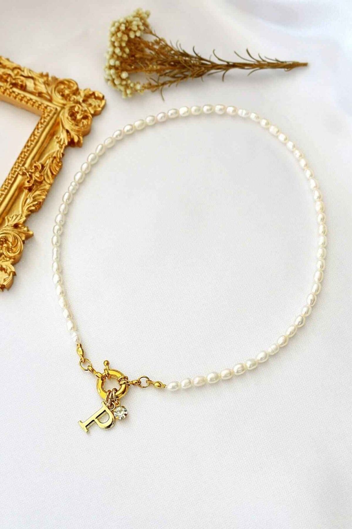 A delicate choker necklace with freshwater pearls and a gold-plated initial charm at the front opening.