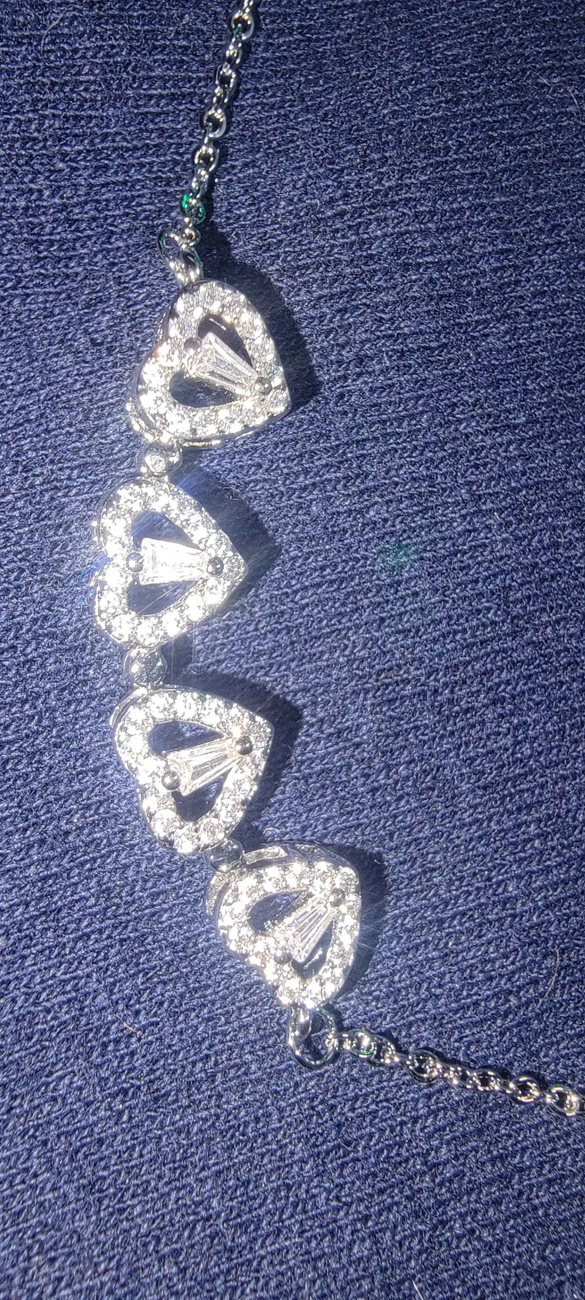Side view of the silver LuckyClover heart and four-leaf clover necklace pendant on white.