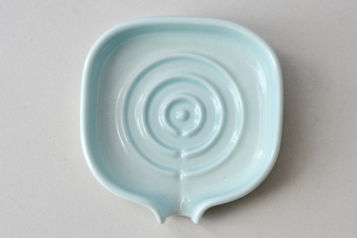 Soap dish holding a bar of soap on a clean bathroom sink area.