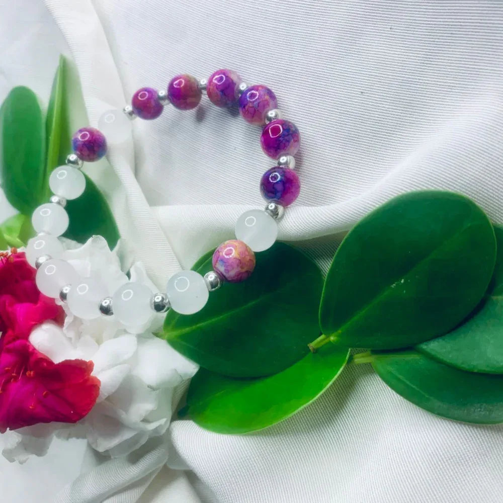 White and purple stone stretch bracelet laid flat showing smooth beads and metallic spacers.
